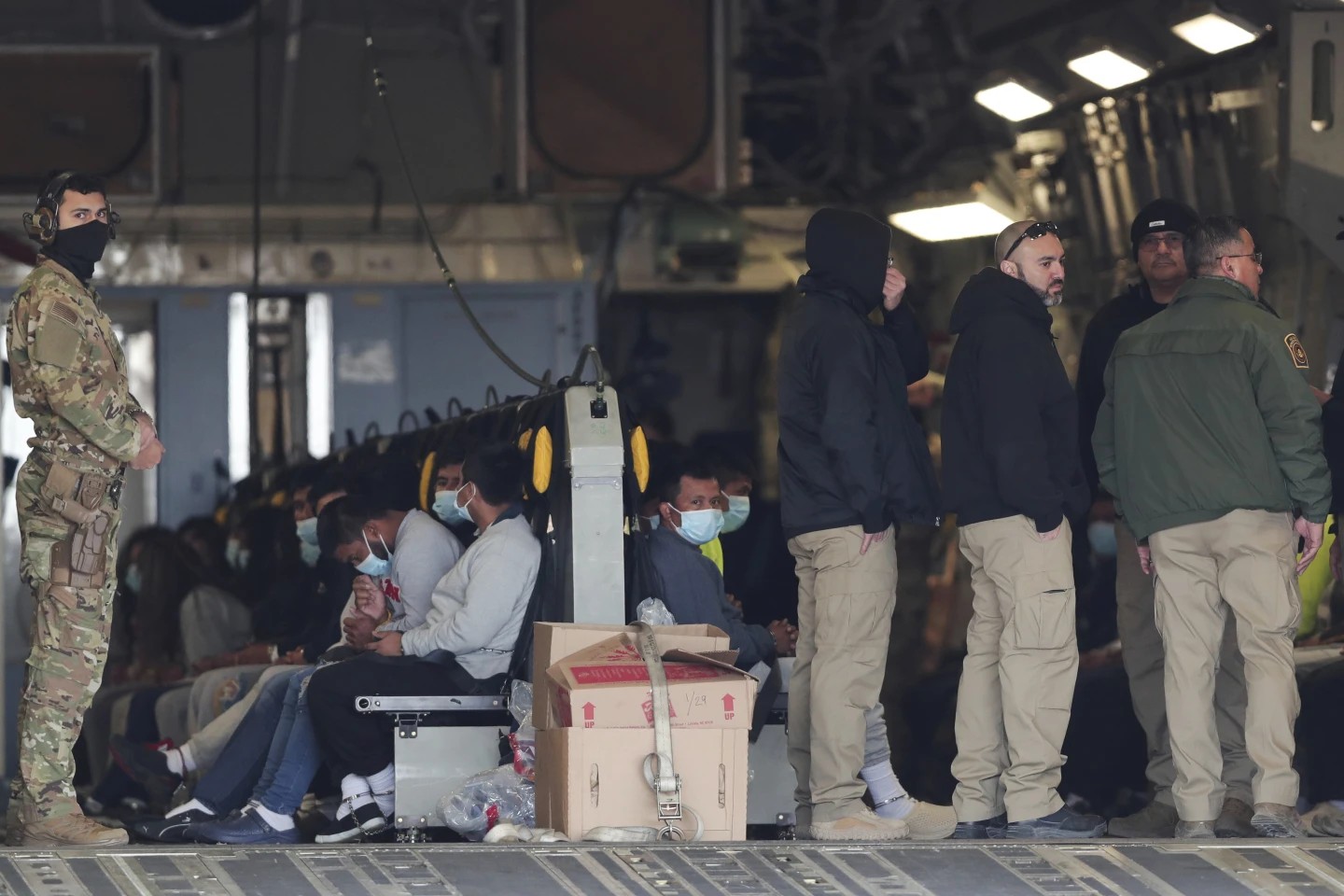 Migrants shackled at their feet and hands are escorted by military personnel as they await their flight to Guatemala. Photo: AP/Christian Chavez Migrants shackled at their feet and hands are escorted by military personnel as they await their flight to Guatemala. Photo: AP/Christian Chavez