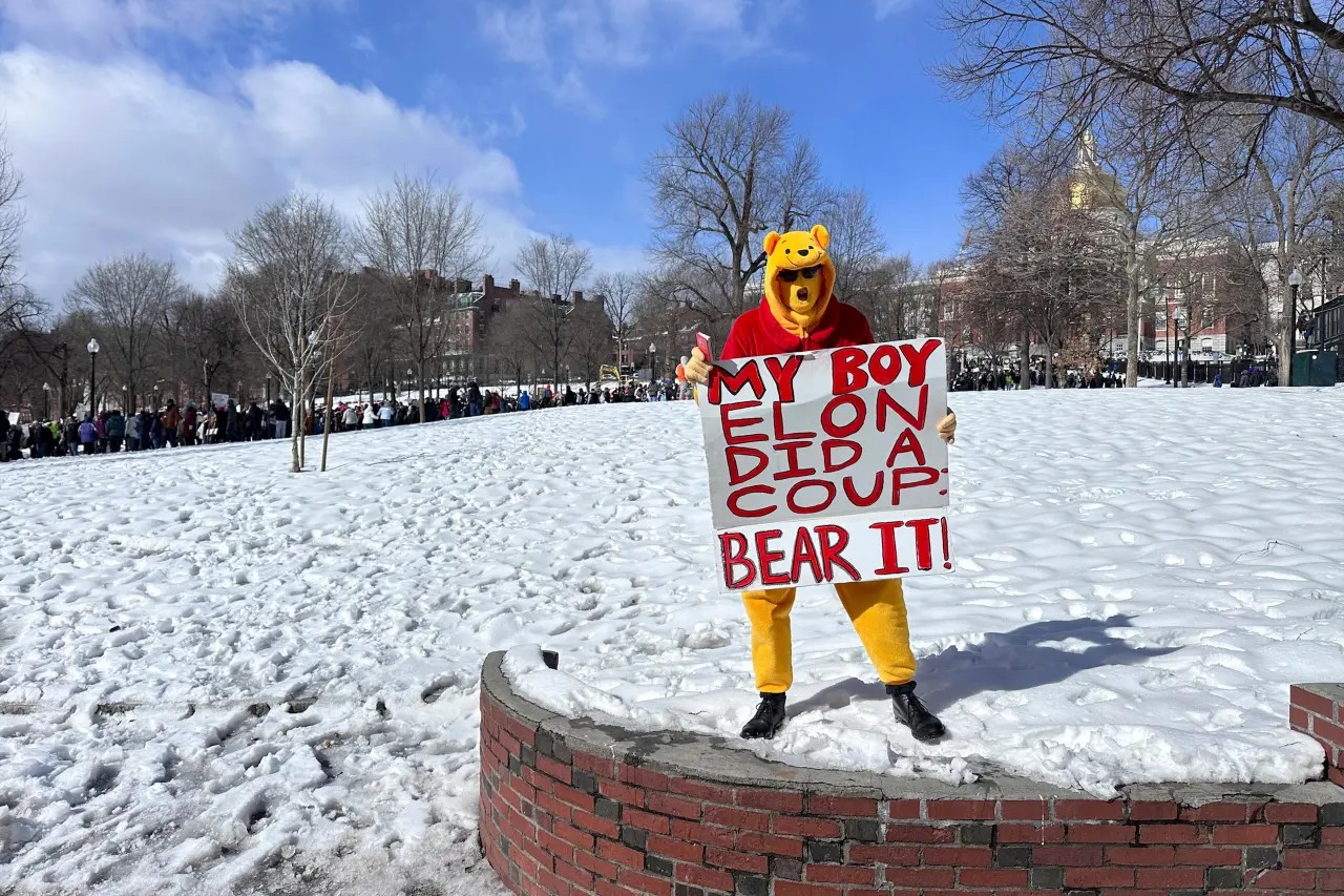 A protester joins more than a thousand people protesting the policies of the Trump administration marched from the Boston Common past City Hall to the North End, Monday, Feb. 17, 2025 in Boston. (AP/Michael Casey) A protester joins more than a thousand people protesting the policies of the Trump administration marched from the Boston Common past City Hall to the North End, Monday, Feb. 17, 2025 in Boston. (AP/Michael Casey)