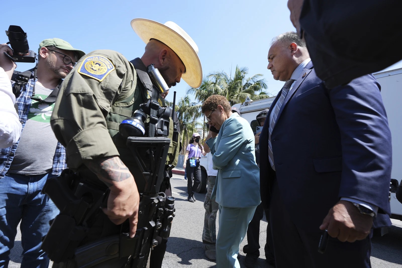 Los Angeles Mayor Karen Bass talks on her mobile phone next to a border patrol federal agent at MacArthur Park Monday, July 7, 2025, in Los Angeles. (AP Photo/Damian Dovarganes)