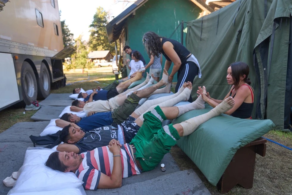 Bomberos toman un descanso para que les masajean los pies un grupo de voluntarias. Foto: AP