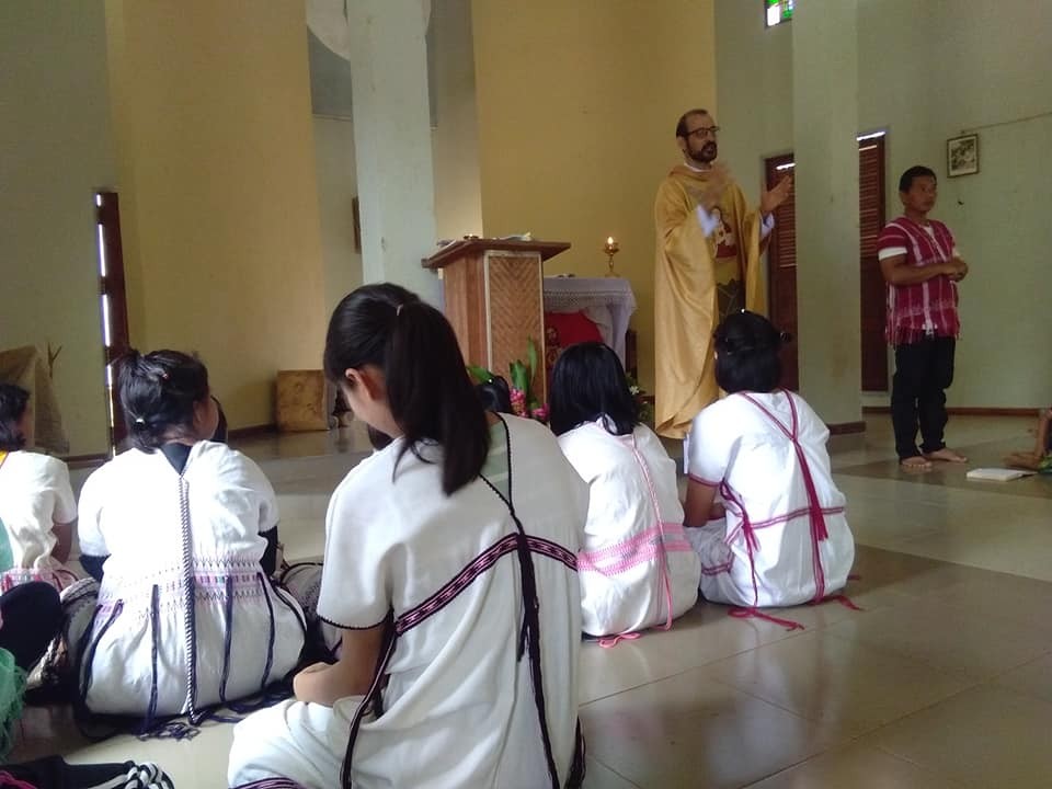 Con una casulla dorada, en lo que fue su parroquia en Tailandia, el padre Camille Rio preside una misa, 2020. Los templos católicos en esa región de Tailandia evitan el uso de bancas o sillas, por ello los fieles están sentados en el piso. Con una casulla dorada, en lo que fue su parroquia en Tailandia, el padre Camille Rio preside una misa, 2020. Los templos católicos en esa región de Tailandia evitan el uso de bancas o sillas, por ello los fieles están sentados en el piso.