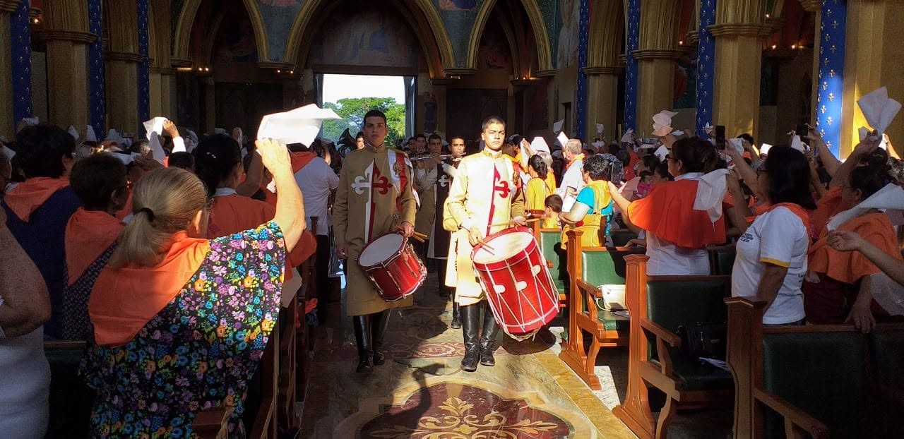 Uma banda musical cujos integrantes usam alguns dos diferentes hábitos dos Arautos entra no Santuário de Nossa Senhora do Bom Conselho, um complexo administrado pelos Arautos em Ypacaraí, Paraguai. Foto: Arautos do Evangelho Paraguai / Facebook, 2019 @ www.facebook.com/photo?fbid=616984998834631&set=pcb.616987142167750.