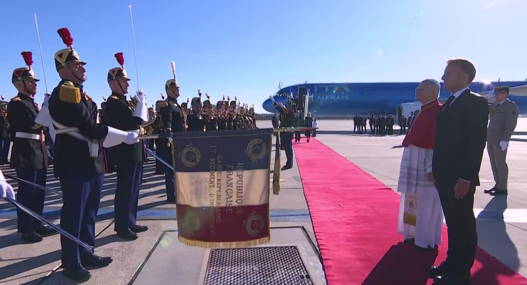Una escolta militar francesa saluda con la bandera al papa León XIV y a Emmanuel Macron en la pista del aeropuerto París-Orly luego de la llegada del pontífice a la capital francesa el 25 de septiembre de 2026. Captura de pantalla del vídeo disponible en el canal de YouTube del Palacio del Elíseo. Una escolta militar francesa saluda con la bandera al papa León XIV y a Emmanuel Macron en la pista del aeropuerto París-Orly luego de la llegada del pontífice a la capital francesa el 25 de septiembre de 2026. Captura de pantalla del vídeo disponible en el canal de YouTube del Palacio del Elíseo.
