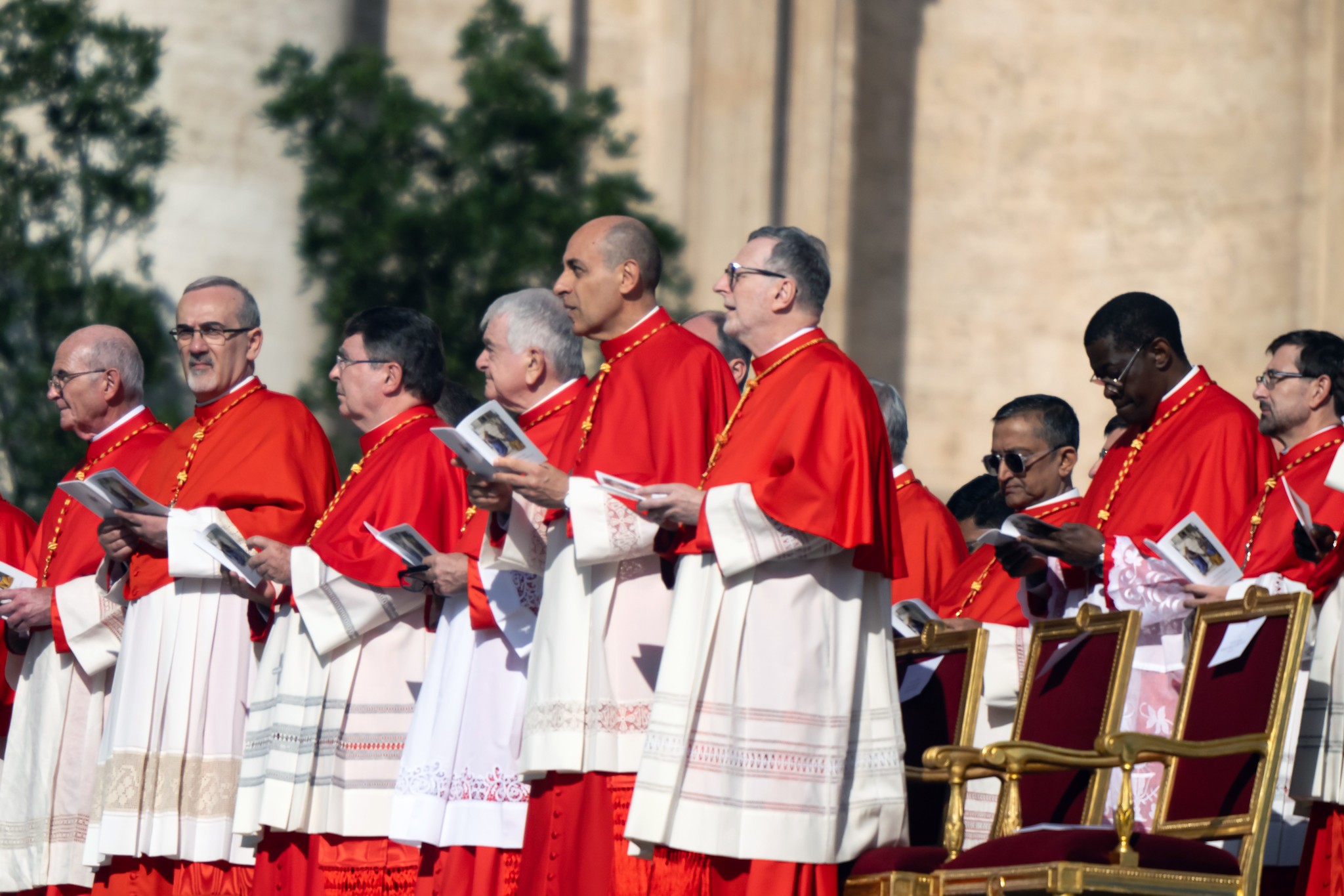Second from right to left, then-Archbishop Fernández holds a booklet during the Consistory where he and 20 other prelates were elevated to cardinals by Pope Francis in 2023. See final note for photo credit.
